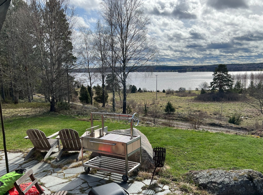 Bild von einem unserer zufriedenen Kunden. Sein kürzlich gekaufter Omberg Asado steht in seinem Garten mit Blick auf die schwedische Ostküste an einem sonnigen Tag.