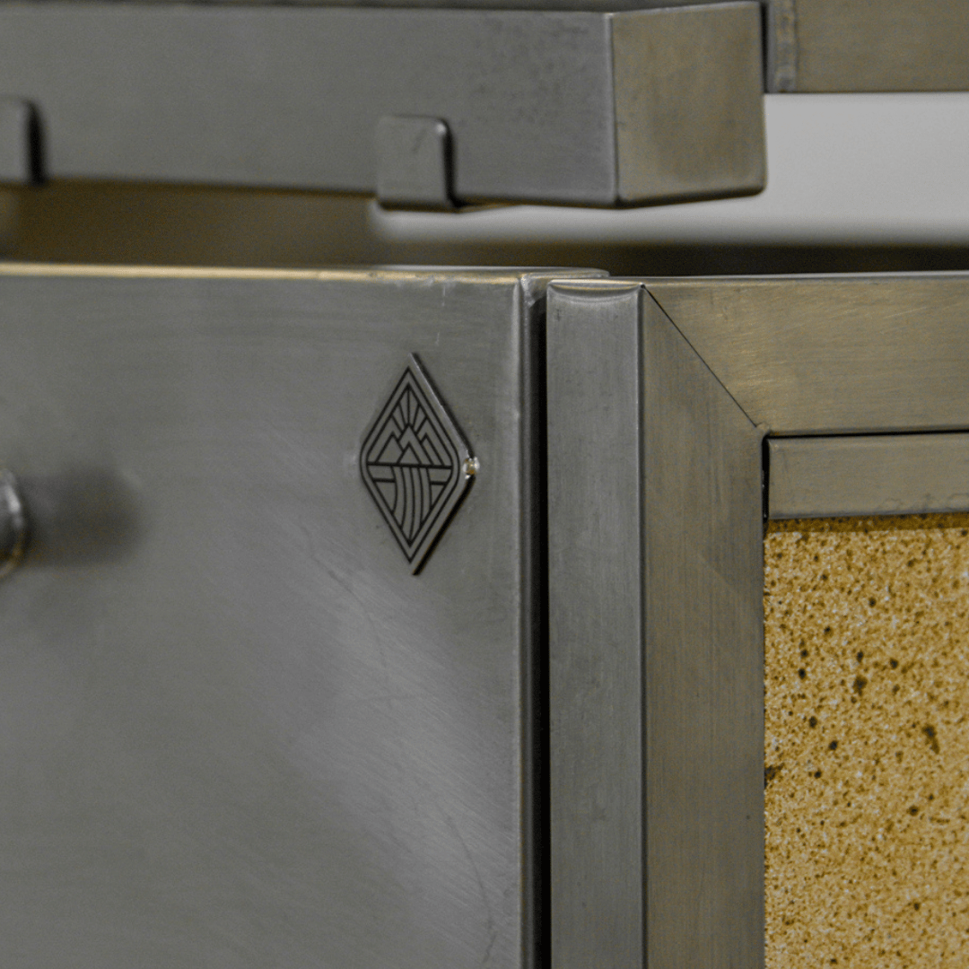 Close-up of a metallic surface with a geometric omberg asado logo